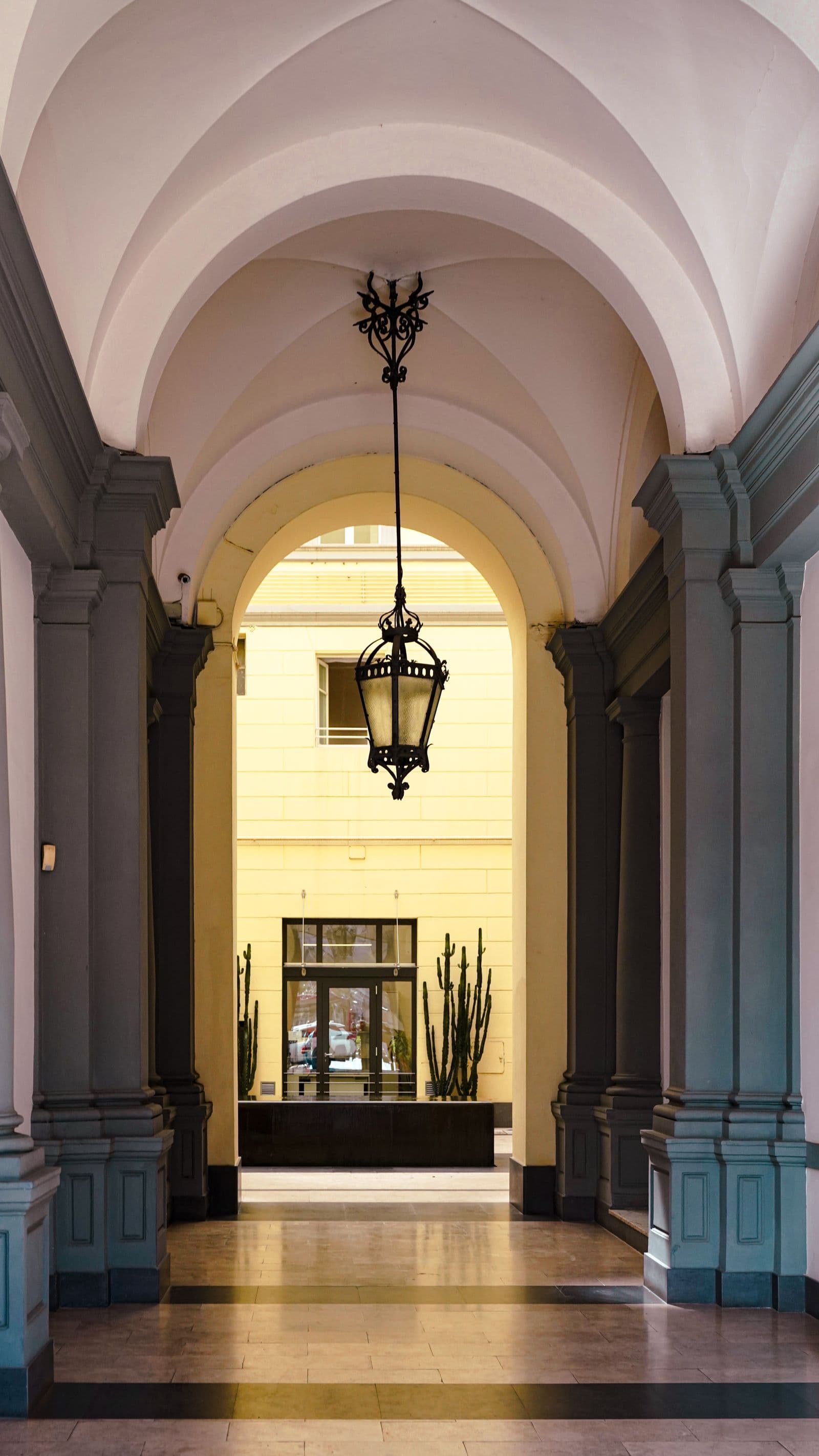 Un passage voûté d'un bâtiment ancien, ouvrant sur une cour claire
